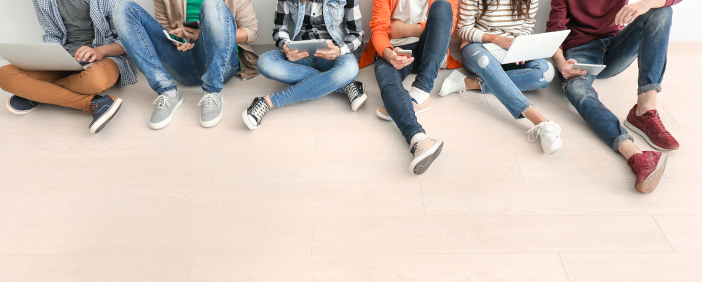 Group of teenagers with modern devices sitting on floor