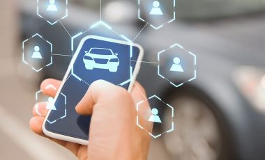 business, transportation and future technology concept - close up of businessman hand with smartphone and virtual car sharing icons